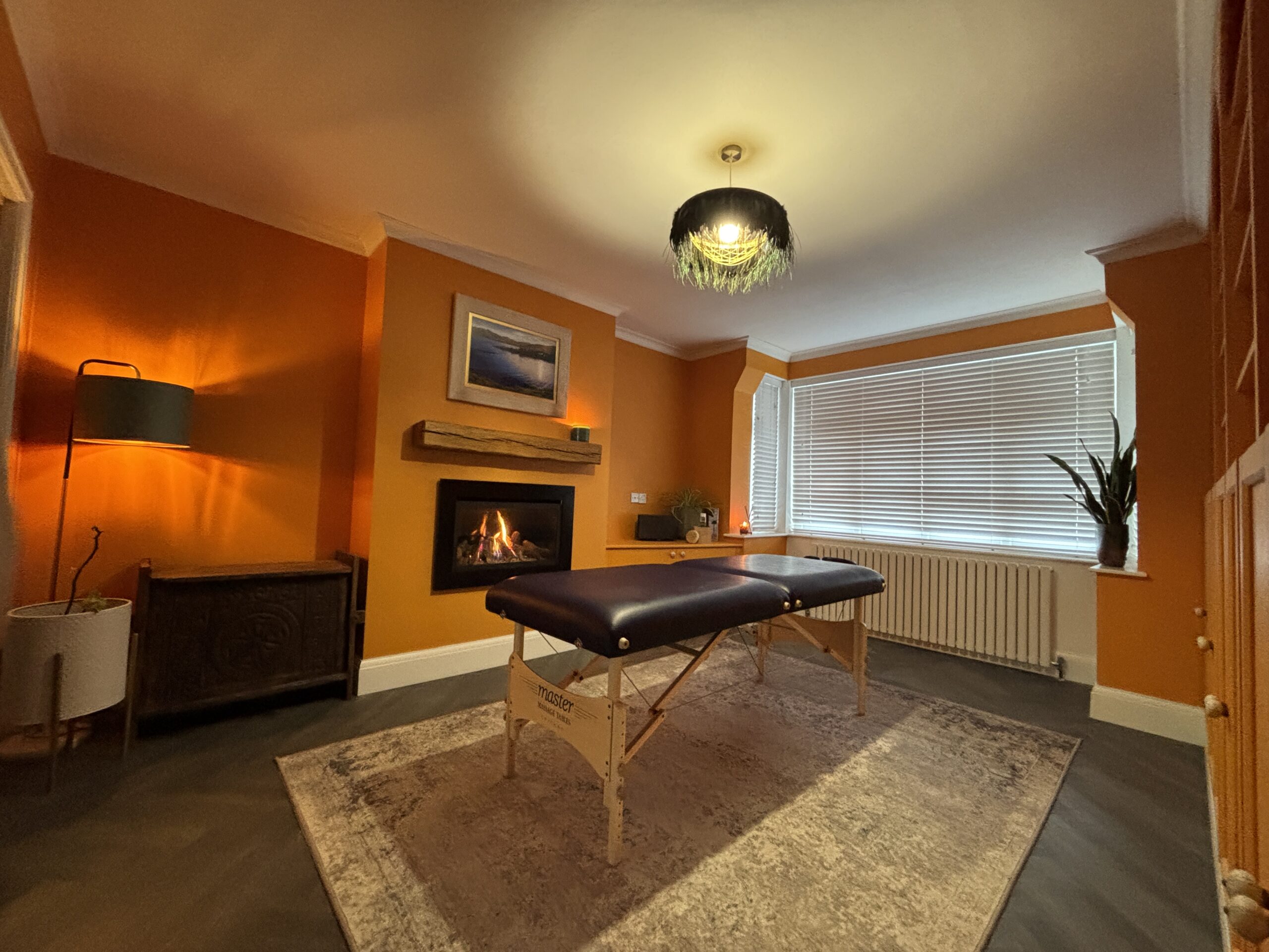 Stillness Health home treatment room in Bristol with massage table, fireplace and calm lighting